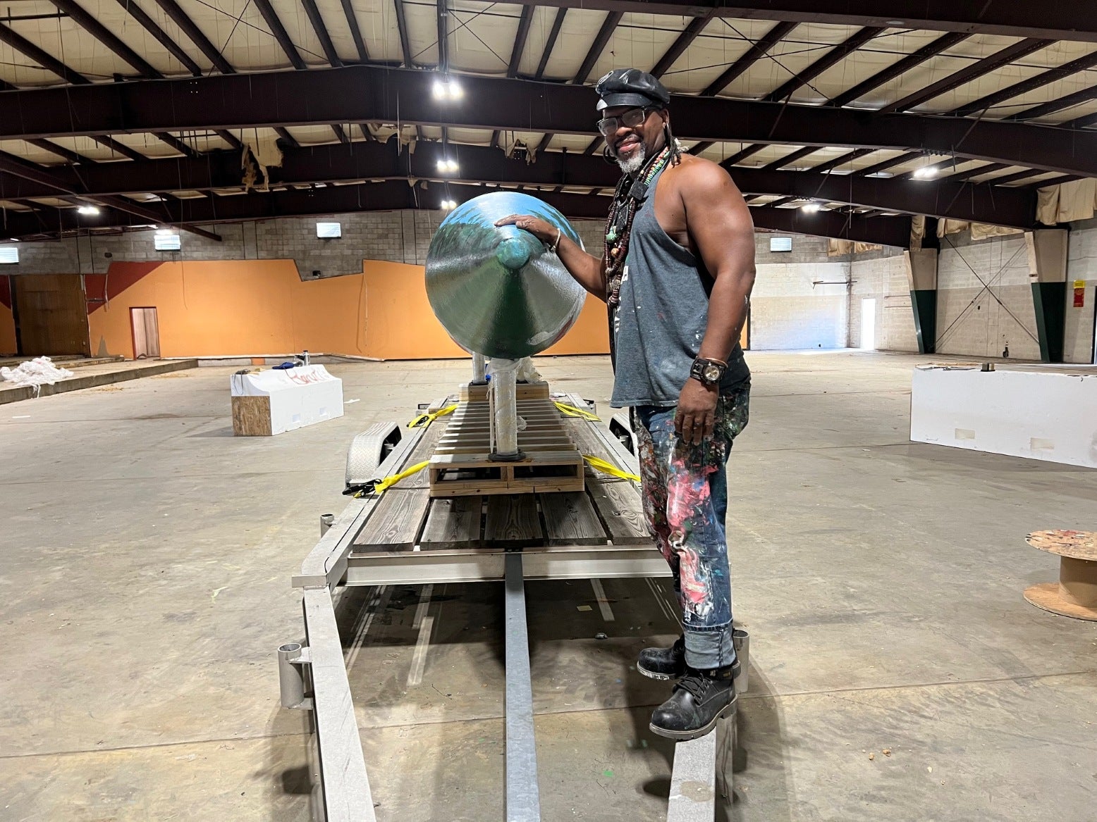 Artist Baruti Tucker with the big tee sculpture he has been painting in an abandoned bowling alley off Gordon Highway in Augusta, Georgia.