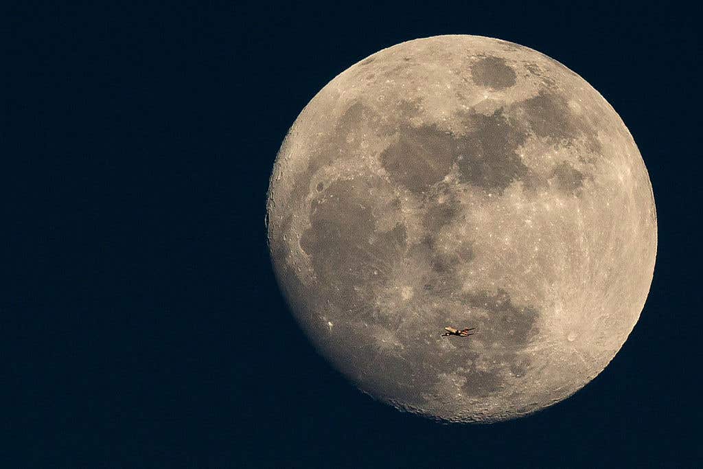 LONDON, ENGLAND: A plane flies past the moon at sunset on March 3, 2015 in London, England. Travel to the moon, and the impact that may have on the lunar landscape and historic sites, is now being considered.