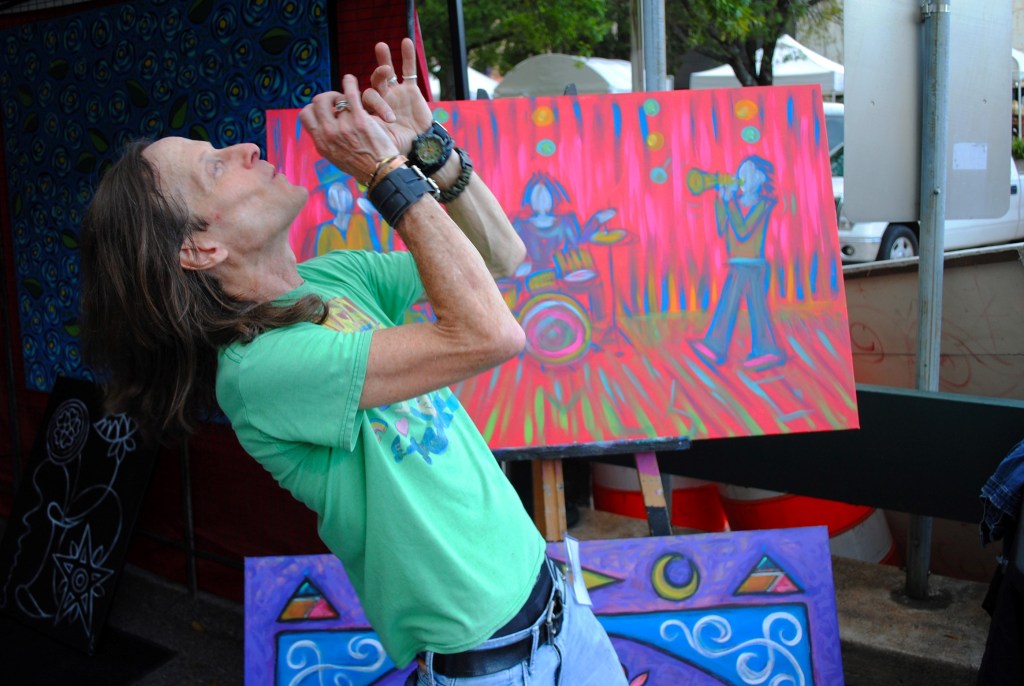 Artist/musician Billy S drawing dramatic inspiration from a work-in-progress at the 2024 Arts In the Heart of Augusta Festival.