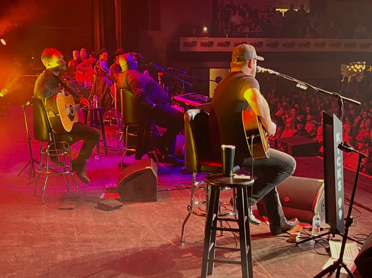 In proper Guitar Pull fashion, performers at the 2024 concert sit in a line, exchanging stories and song in front of an enthusiastic audience.